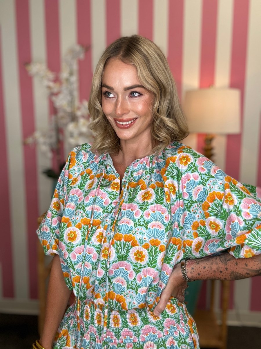 Woman wearing a floral dress in a room with striped wallpaper