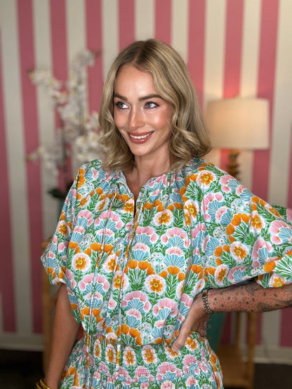 Woman wearing a floral dress in a room with striped wallpaper
