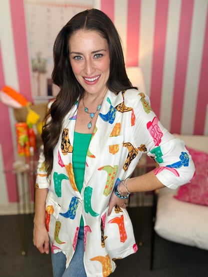 Woman wearing a colorful patterned jacket in a room with pink and white striped walls.