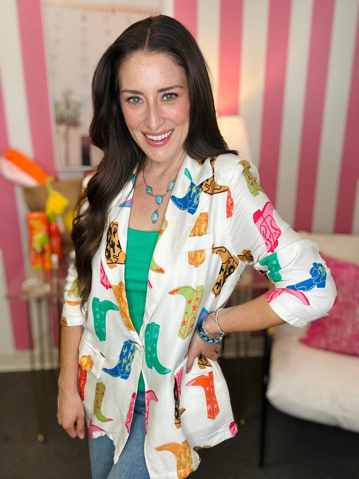 Woman wearing a colorful patterned jacket in a room with pink and white striped walls.