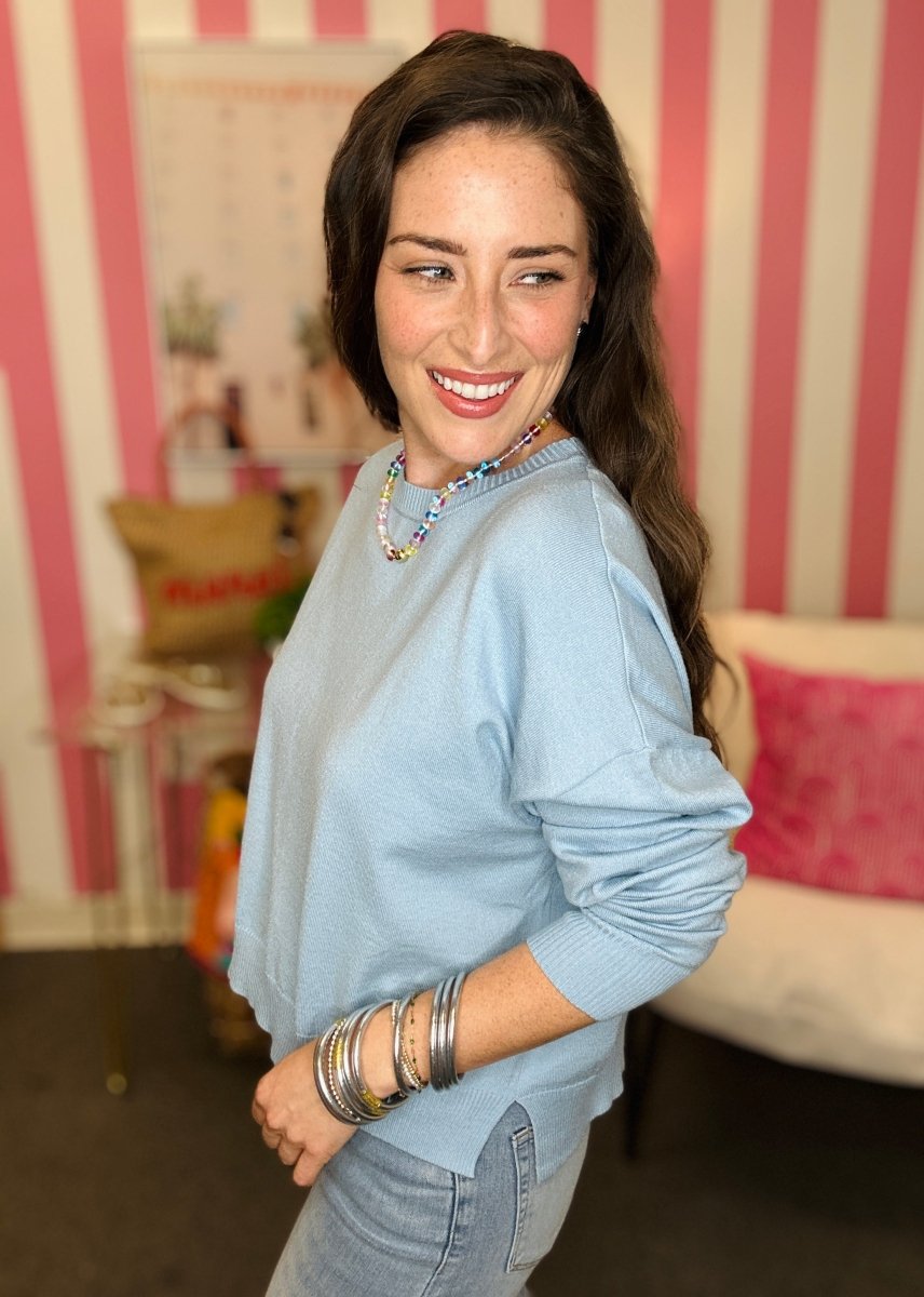Woman wearing a light blue shirt with a striped wall in the background