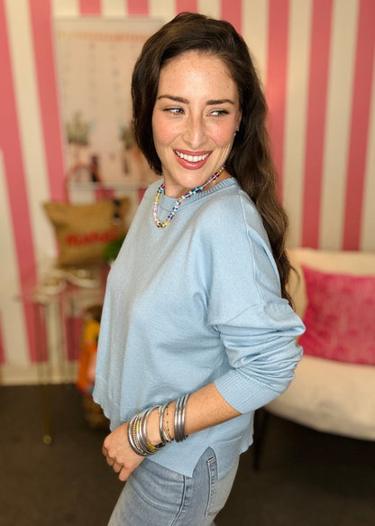 Woman wearing a light blue shirt with a striped wall in the background
