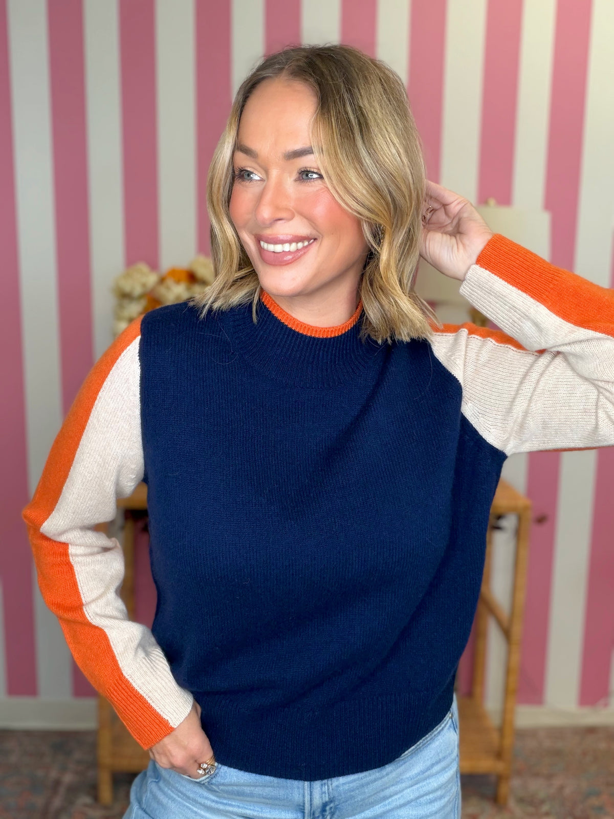 woman standing in a blue top with orange stripes