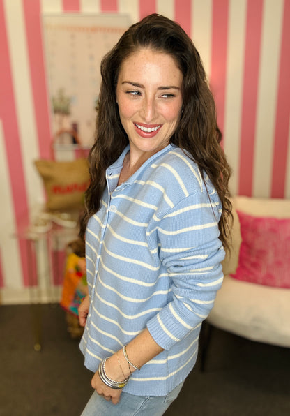 Woman wearing a blue and white striped sweater in a room with pink and white striped wallpaper.