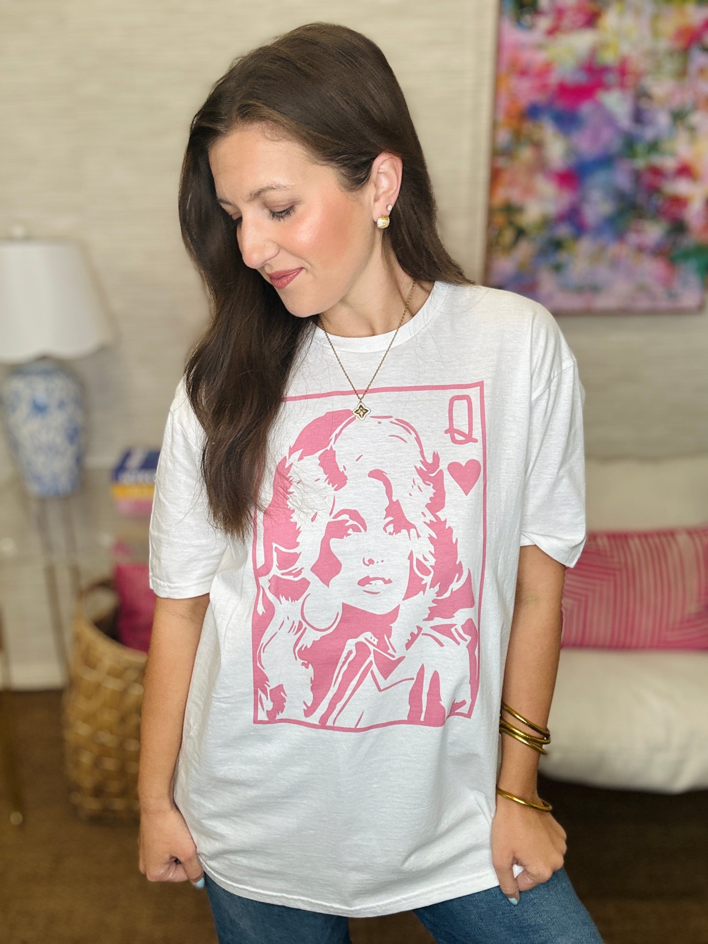 Woman wearing a white t-shirt with a pink graphic design in a room.