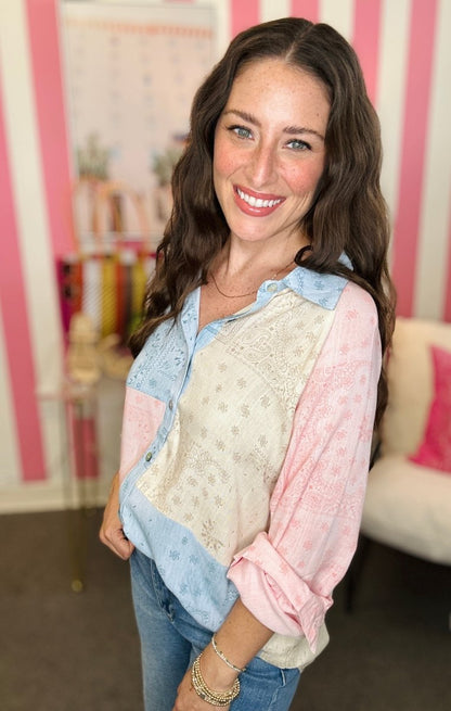 Woman wearing a layered outfit with a pink and blue patterned shirt in a room with striped walls.
