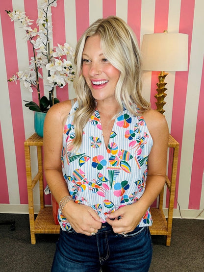 Woman wearing a colorful floral top in a room with striped walls and a lamp.