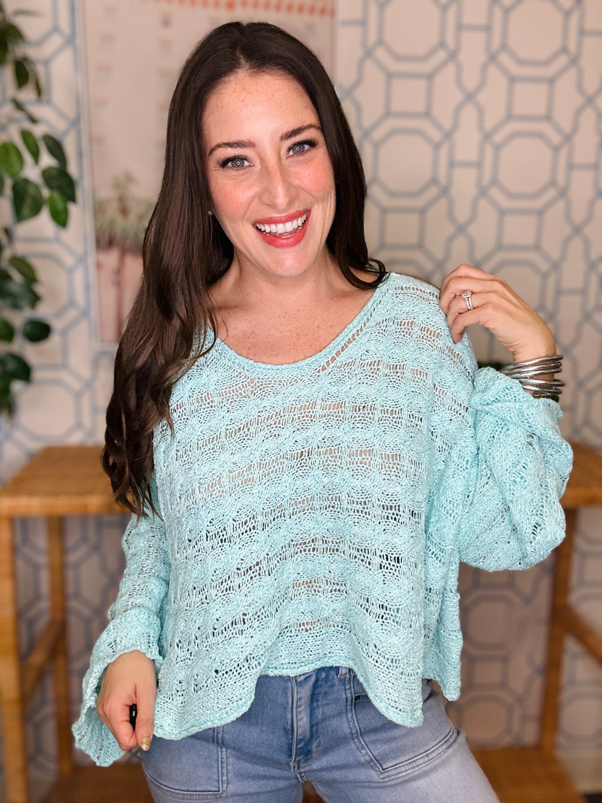 Woman wearing a light blue sweater with pattern indoors.