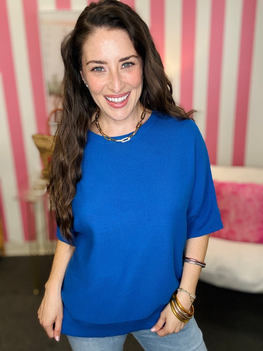 Woman wearing a blue shirt with a striped pink and white wall in the background