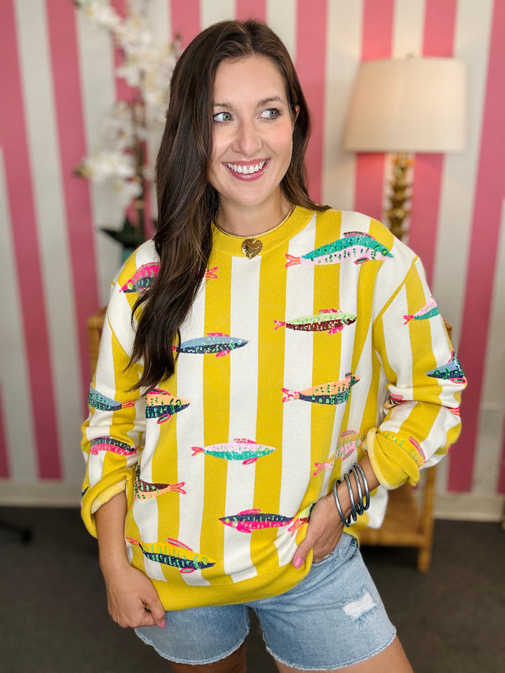 Woman wearing a yellow and white patterned sweater with a striped background