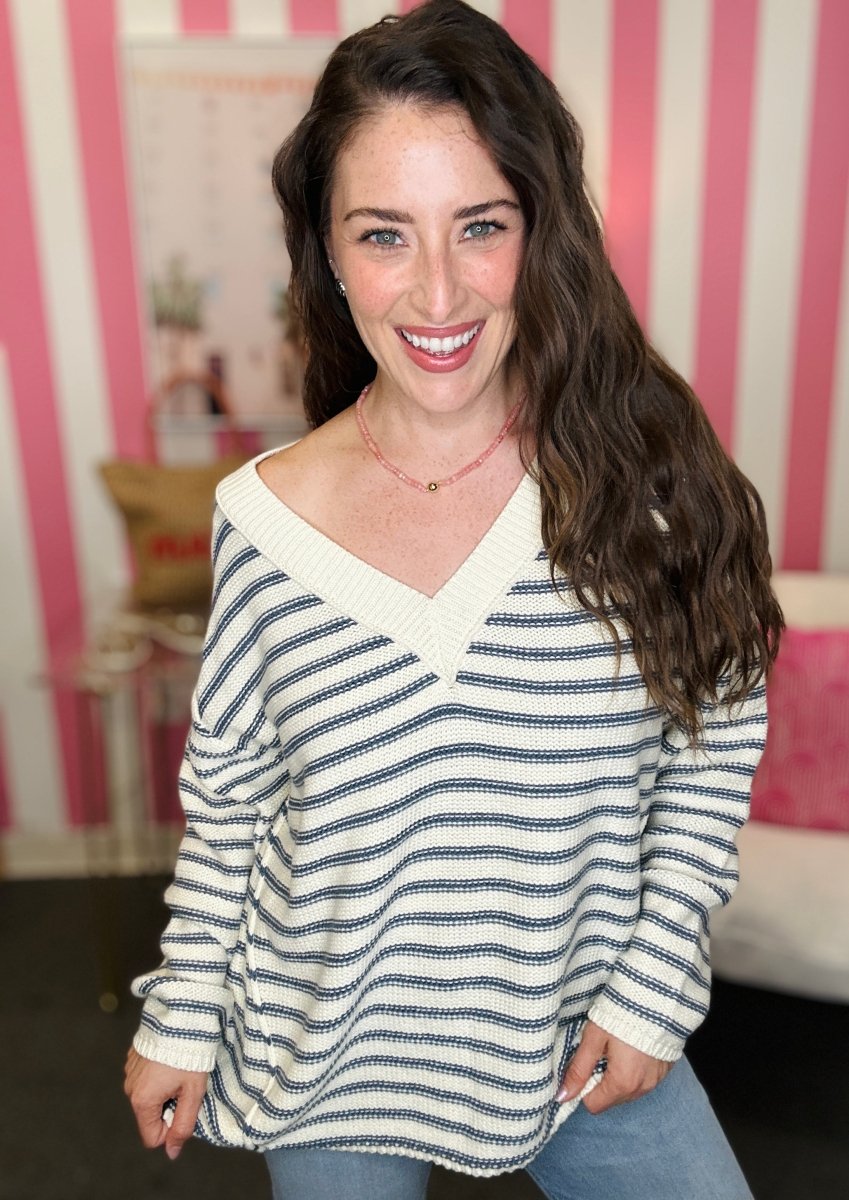Woman wearing a striped sweater in a room with pink and white striped walls.