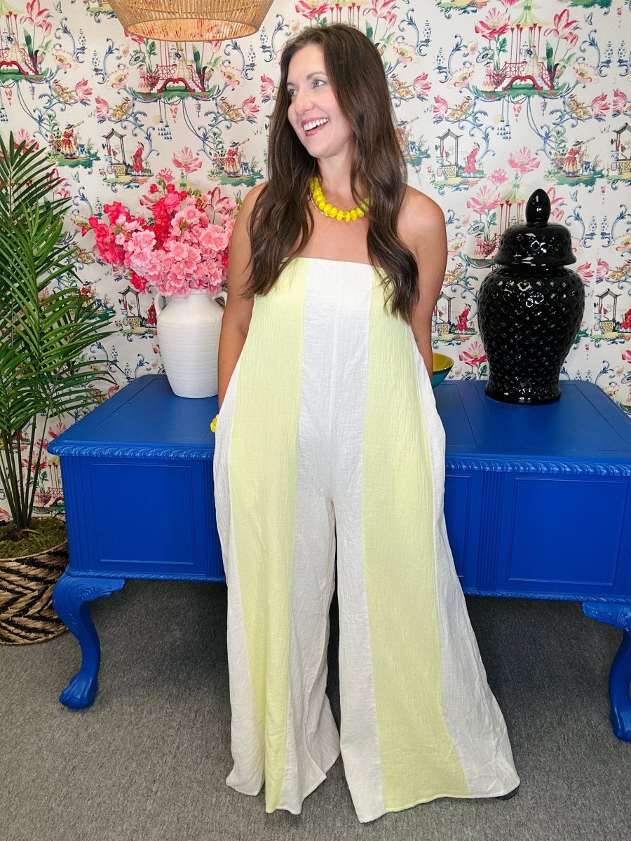 Woman in a yellow and white dress standing in front of a colorful wall with floral patterns.