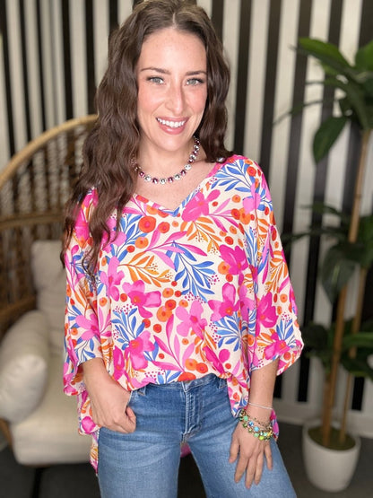 Woman wearing a colorful floral blouse and jeans indoors.