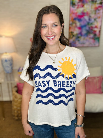 Woman wearing a white t-shirt with a sun and wave design and 'EASY BREEZY' text.