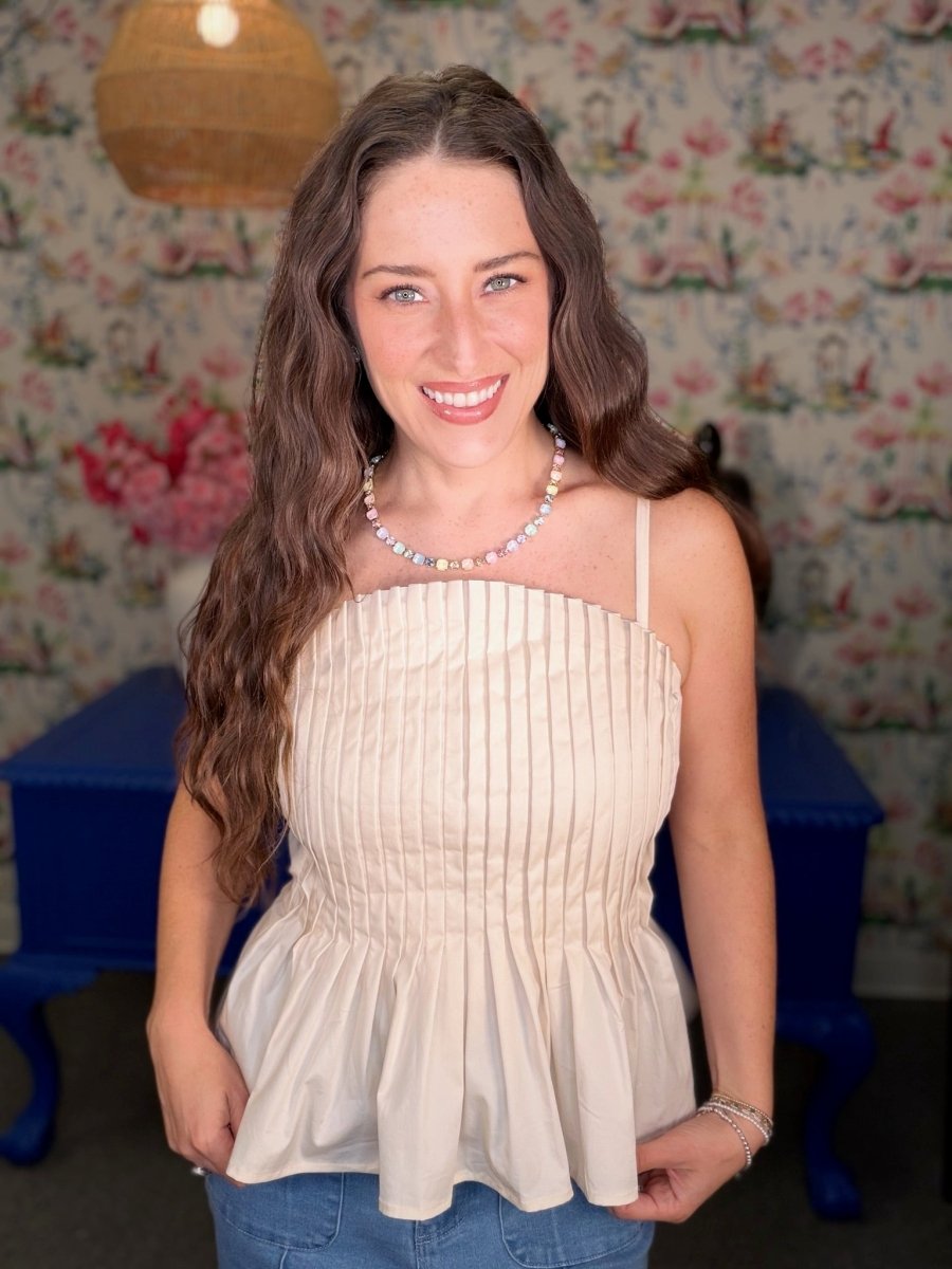 Woman wearing a white top and blue jeans in a room with floral wallpaper.