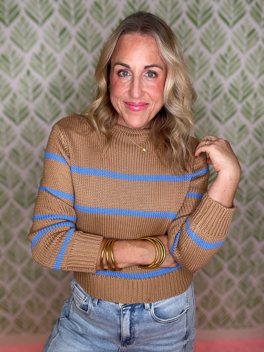 woman standing in room in striped sweater and jeans