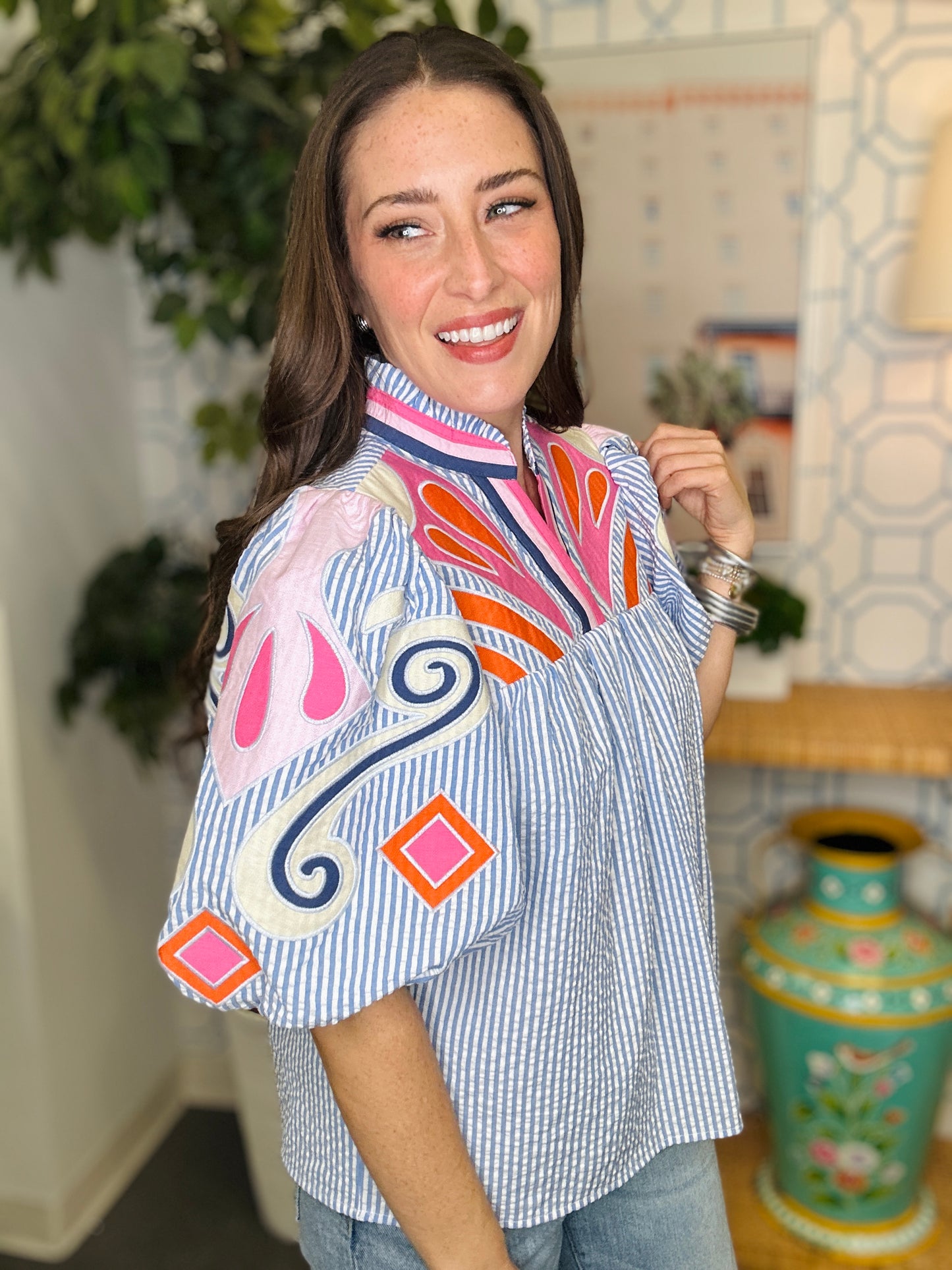 Woman wearing a colorful blouse with abstract patterns in a home setting