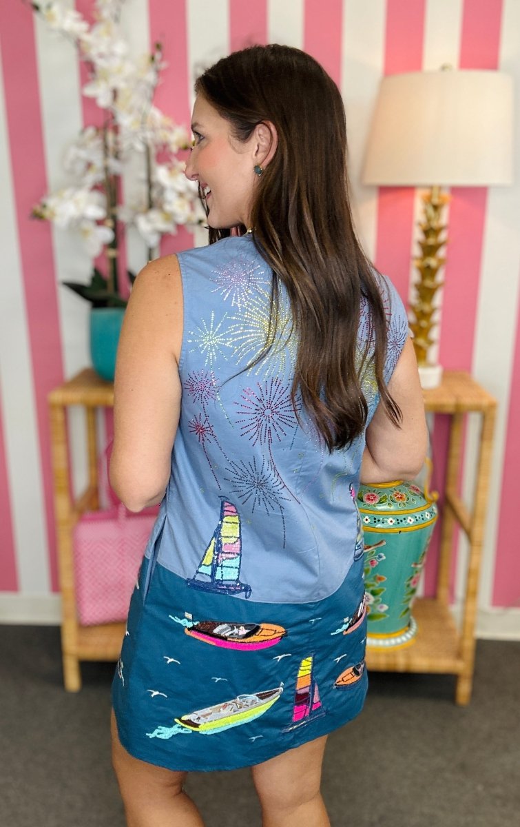 Woman wearing a blue sleeveless top and skirt with colorful designs in a room with striped walls.