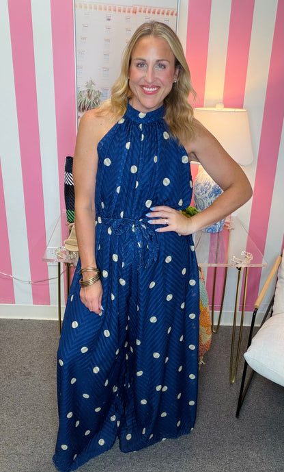 Woman wearing a blue polka dot dress in an indoor setting with striped walls.