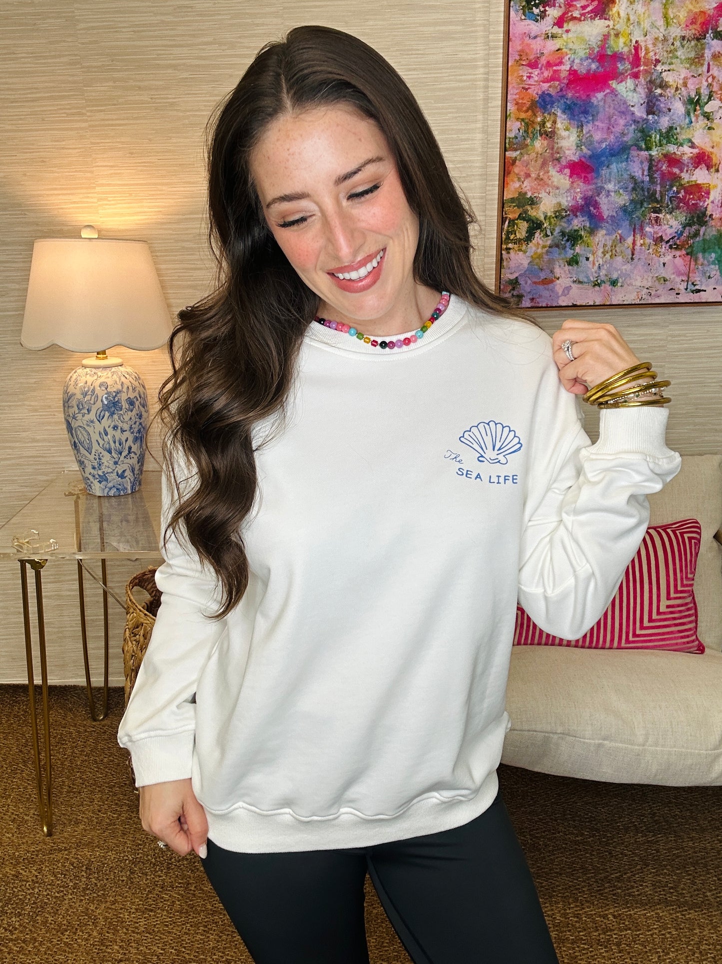 Woman wearing a white sweatshirt with a logo in a living room setting