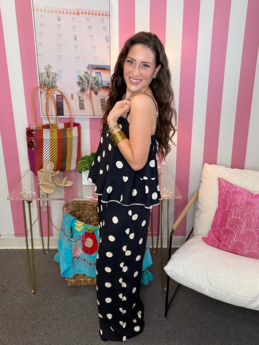 Woman in a polka dot dress standing in a room with striped walls and decorative items.