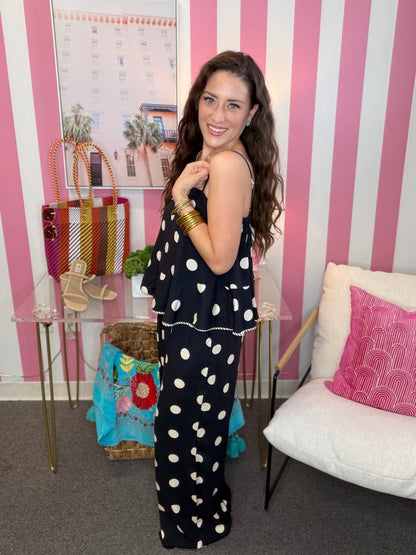 Woman in a polka dot dress standing in a room with striped walls and decorative items.