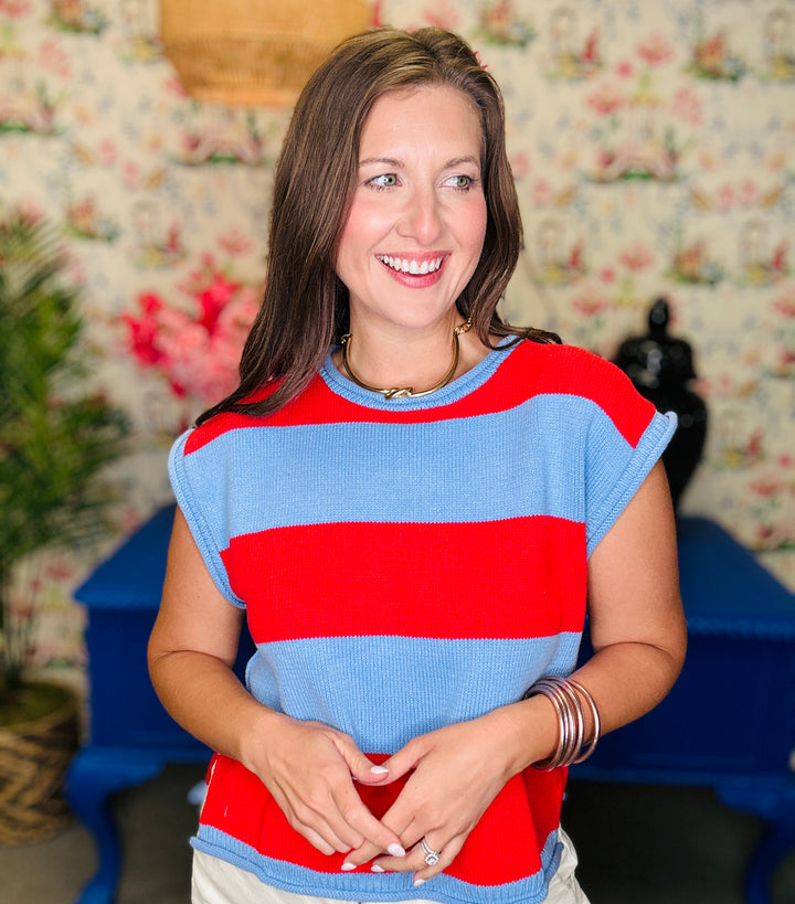Woman wearing a red and blue striped shirt with a floral wallpaper background