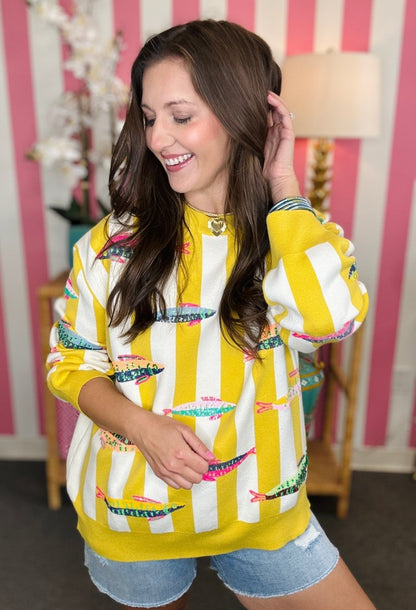 Woman wearing a yellow and white patterned sweater with a striped background