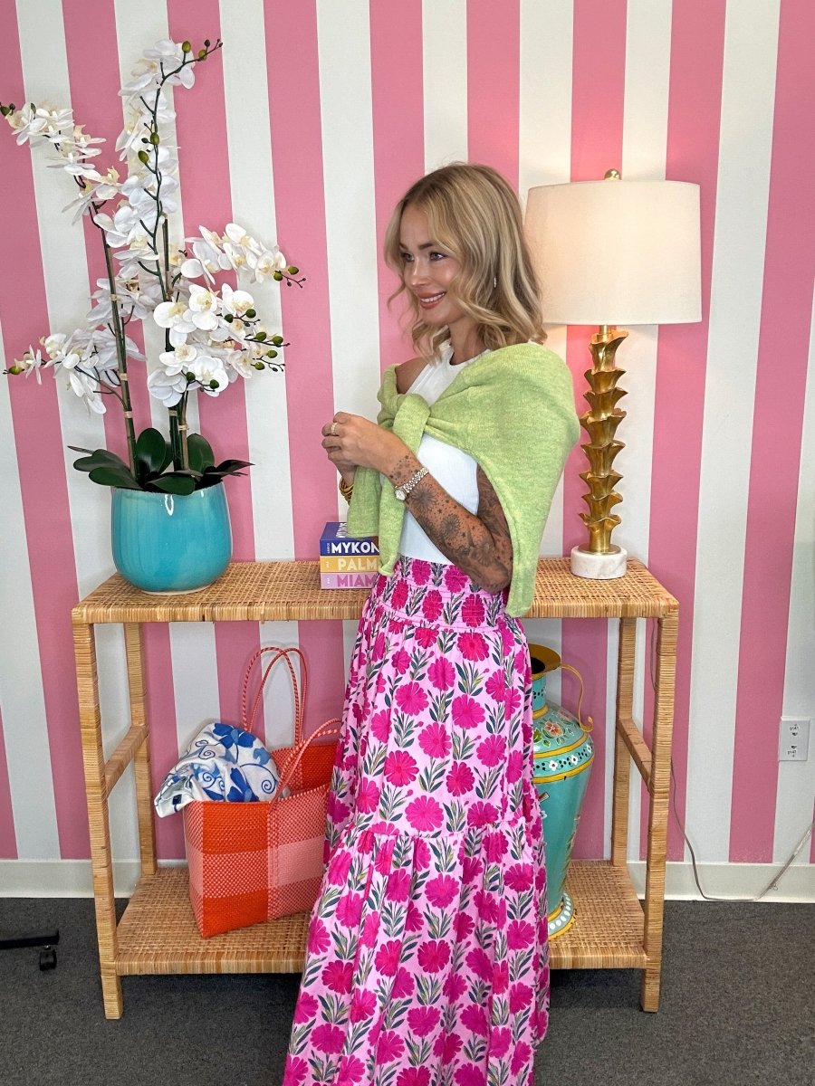 Woman standing in a room with pink and white striped wallpaper, holding a green shawl.