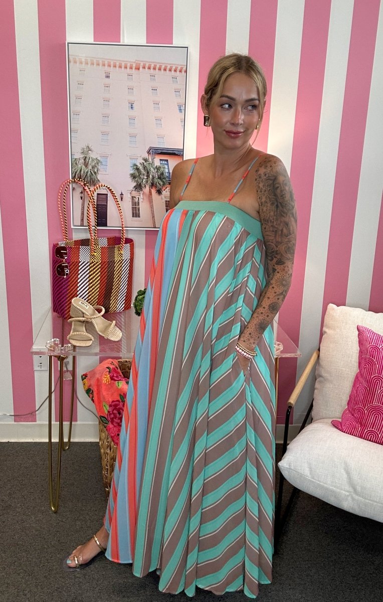 Woman in a striped dress standing in a room with pink and white striped walls.