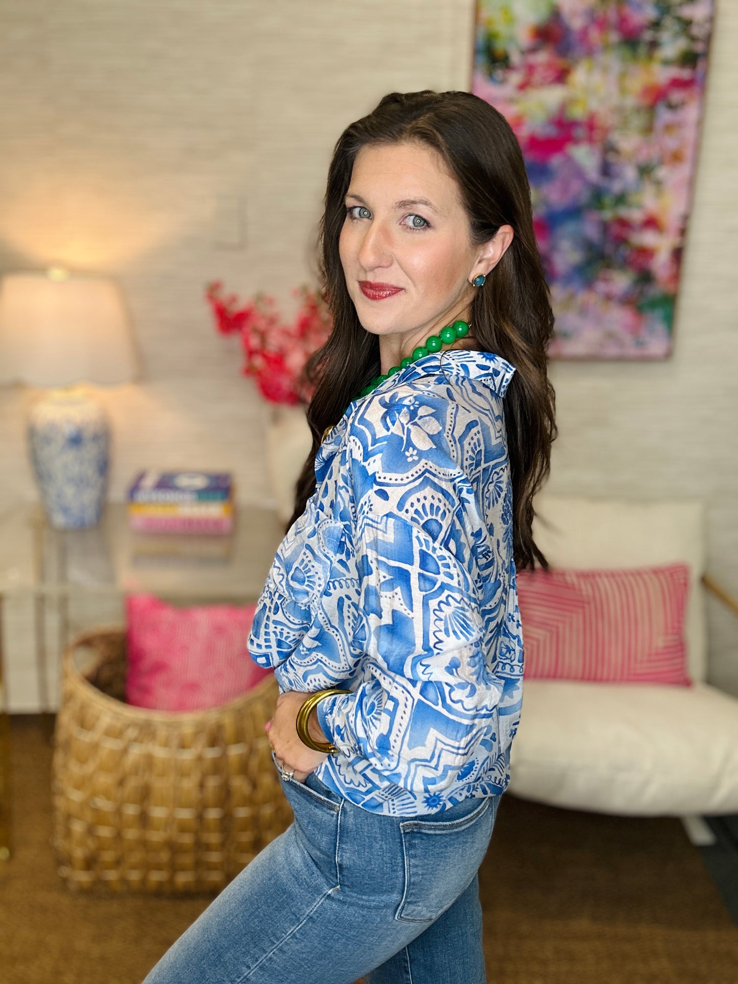 Woman wearing a blue patterned blouse and jeans in a living room setting.