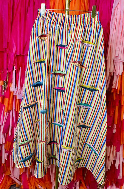 Colorful striped pants hanging on a rack with colorful umbrellas in the background