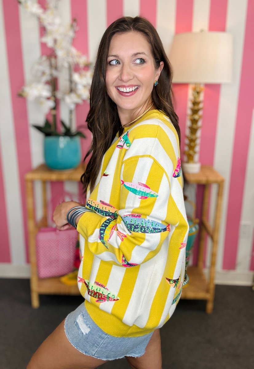 Woman wearing a yellow and white patterned sweater with a striped background