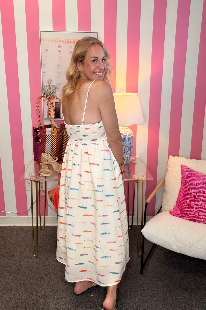 Woman in a colorful dress standing in a room with pink and white striped walls.
