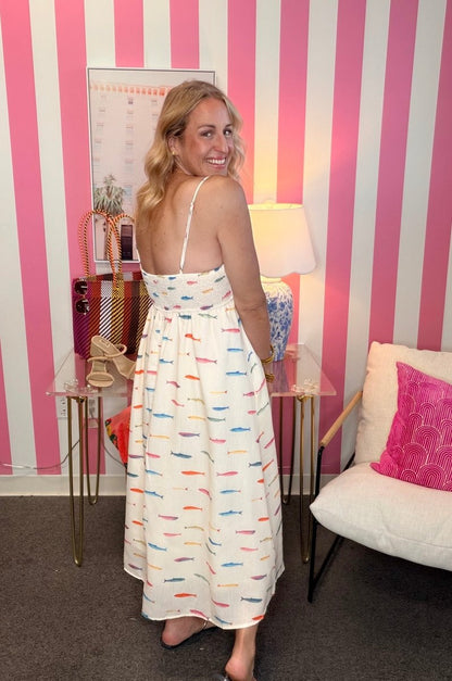 Woman in a colorful dress standing in a room with pink and white striped walls.