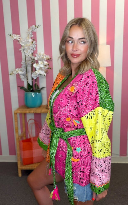 Woman wearing a colorful, patterned robe in a room with striped walls and a lamp.