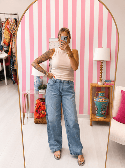 Person taking a mirror selfie in a room with pink and white striped wallpaper.