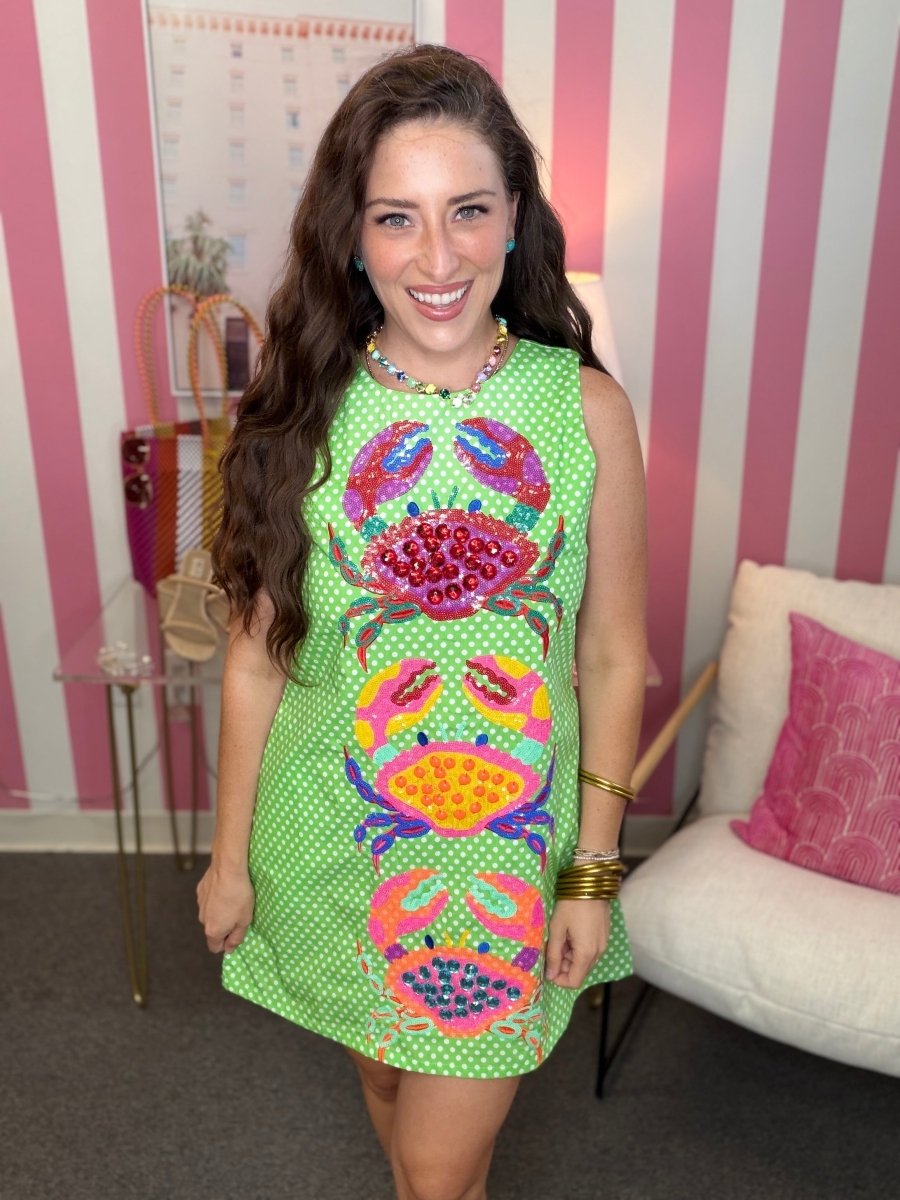 Woman wearing a colorful dress with crab patterns in a room with striped walls.