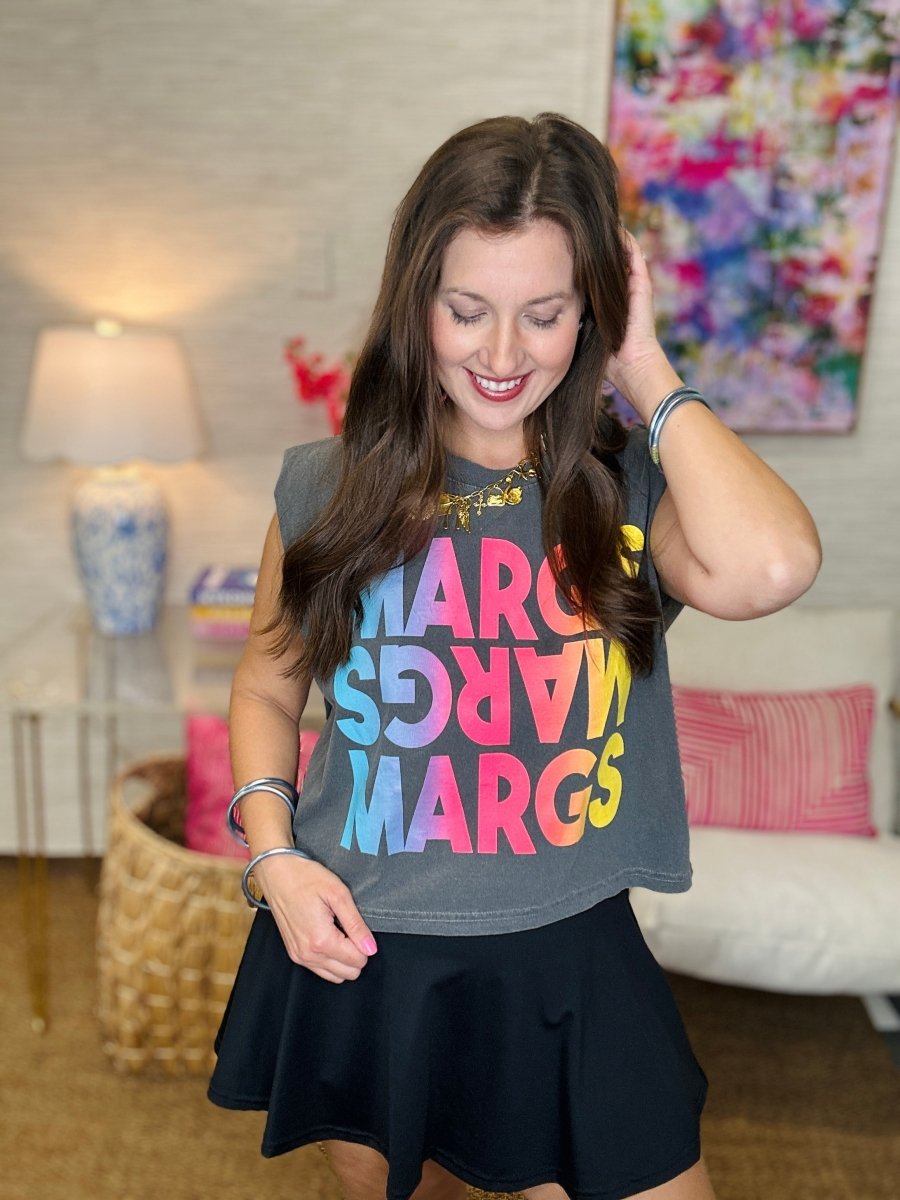 Woman wearing a colorful 'MARGS' t-shirt in a living room setting