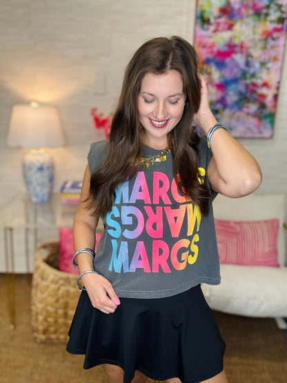 Woman wearing a colorful 'MARGS' t-shirt in a living room setting