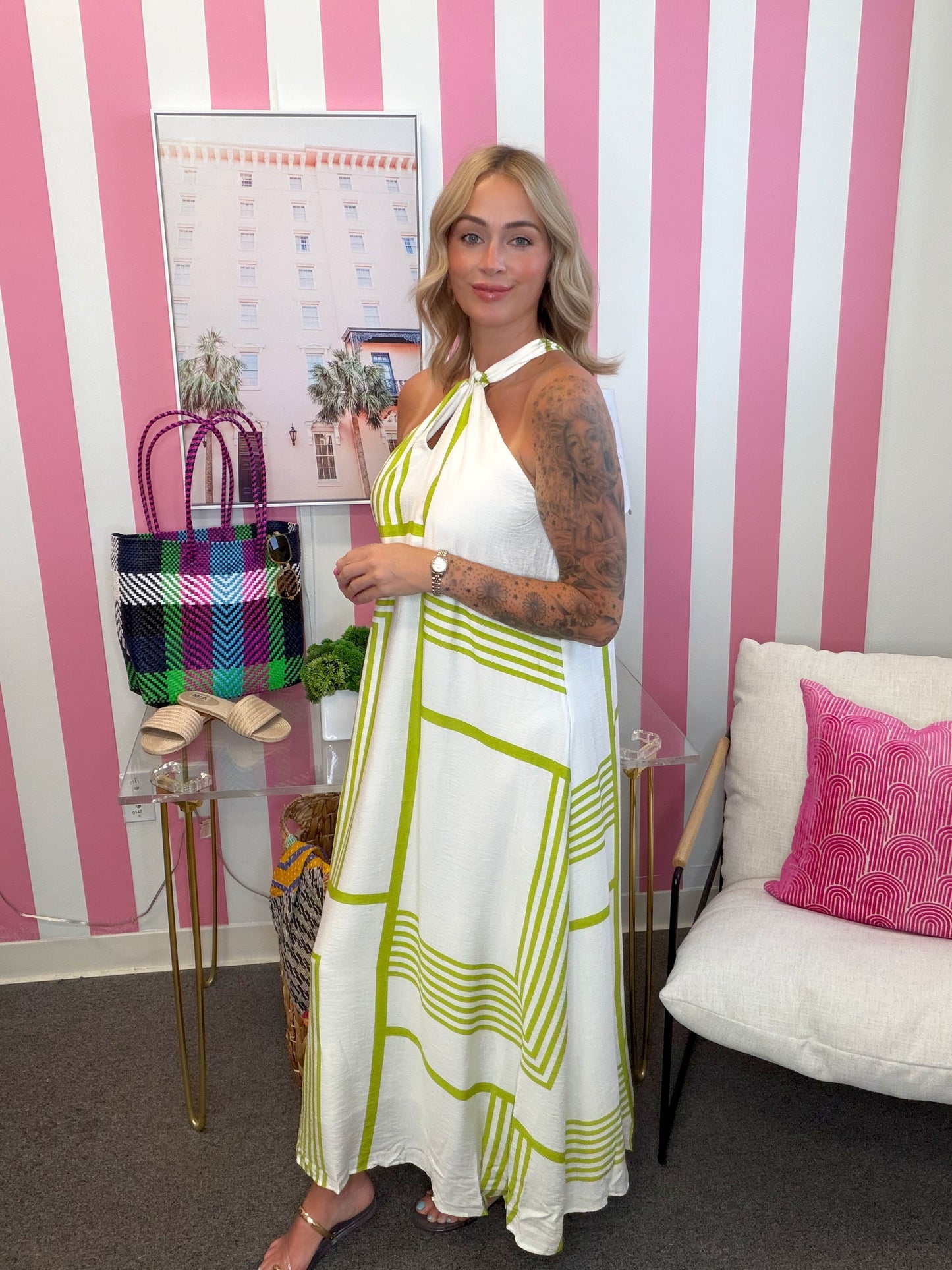 Woman in a white and green dress standing in a room with pink and white striped walls.