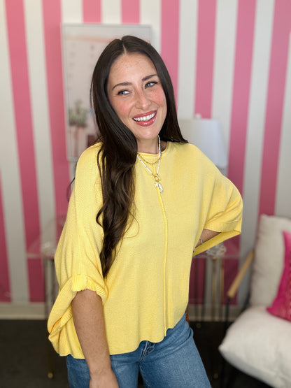 Woman wearing a yellow top and blue jeans in a room with pink and white striped walls.