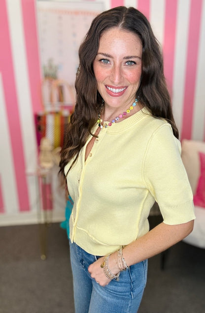 Woman wearing a yellow top and blue jeans in a room with pink and white striped walls.