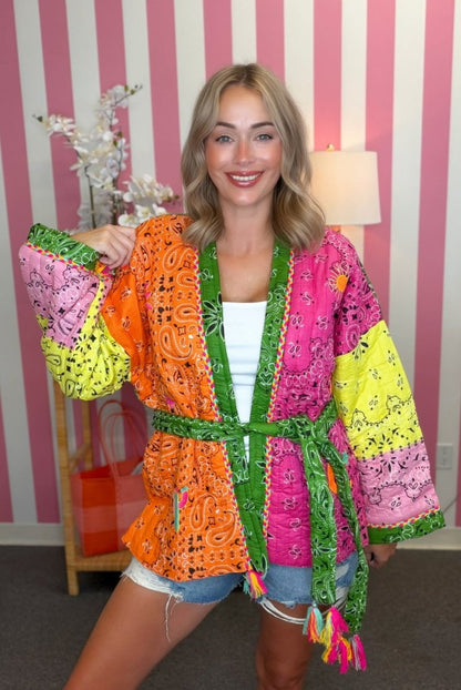 Woman wearing a colorful, patterned kimono in a room with striped wallpaper.