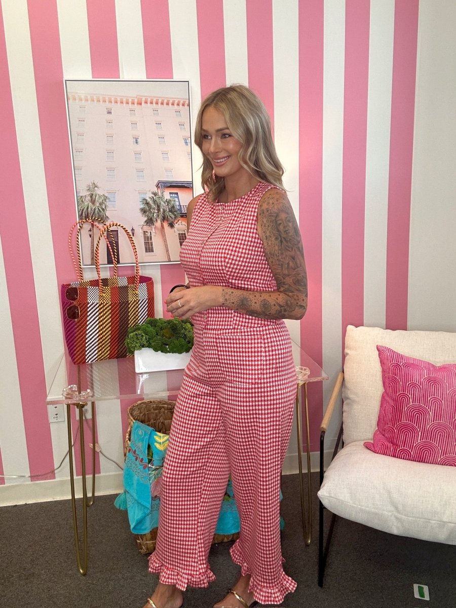 Woman in a pink checkered outfit standing in a room with pink and white striped walls.