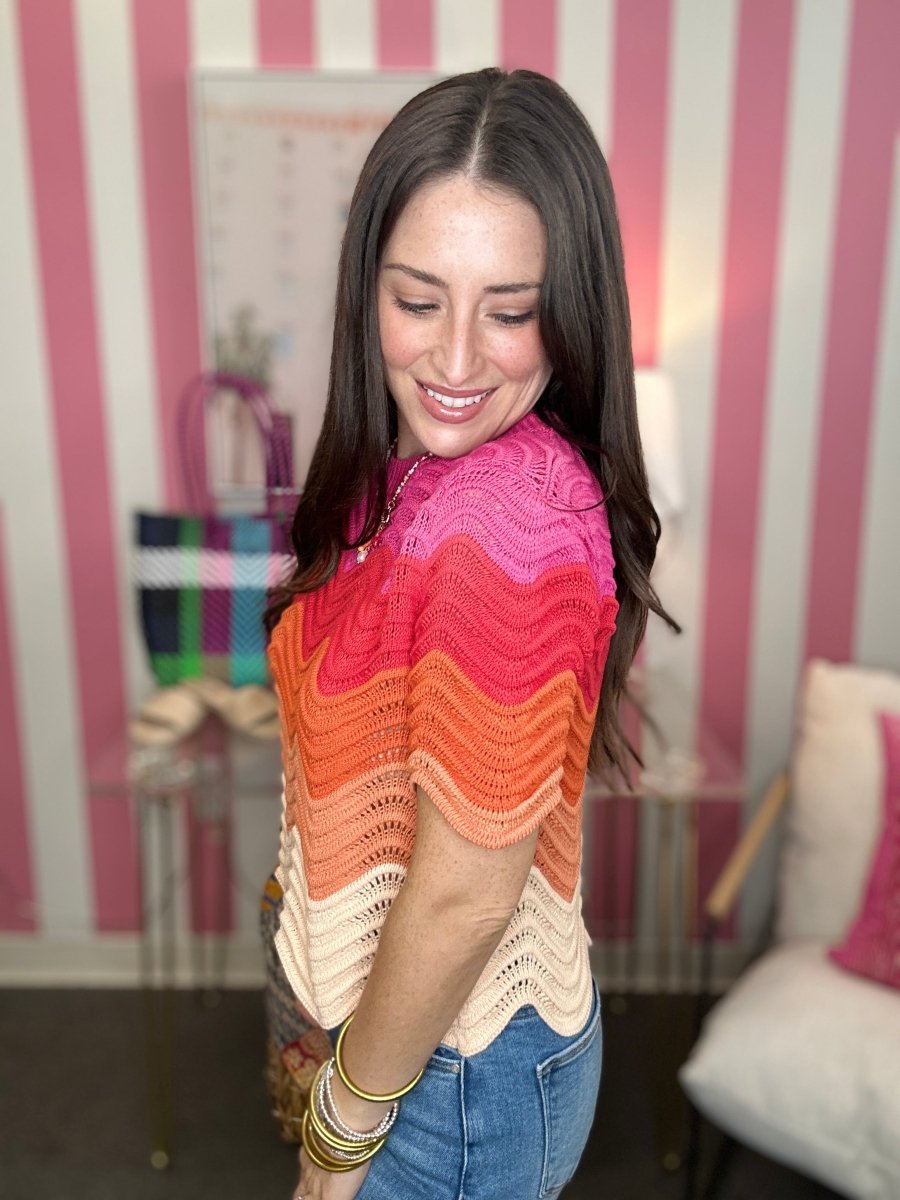 Woman wearing a colorful, patterned sweater in a room with striped walls.