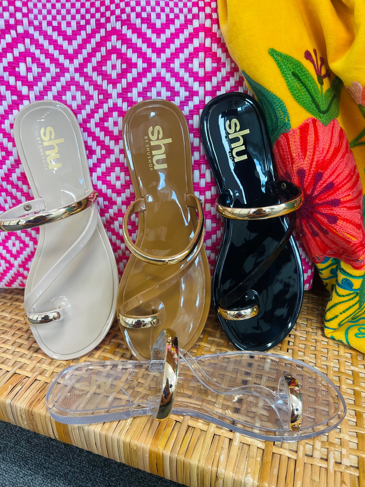 Three pairs of sandals with 'shu' branding on a woven surface.