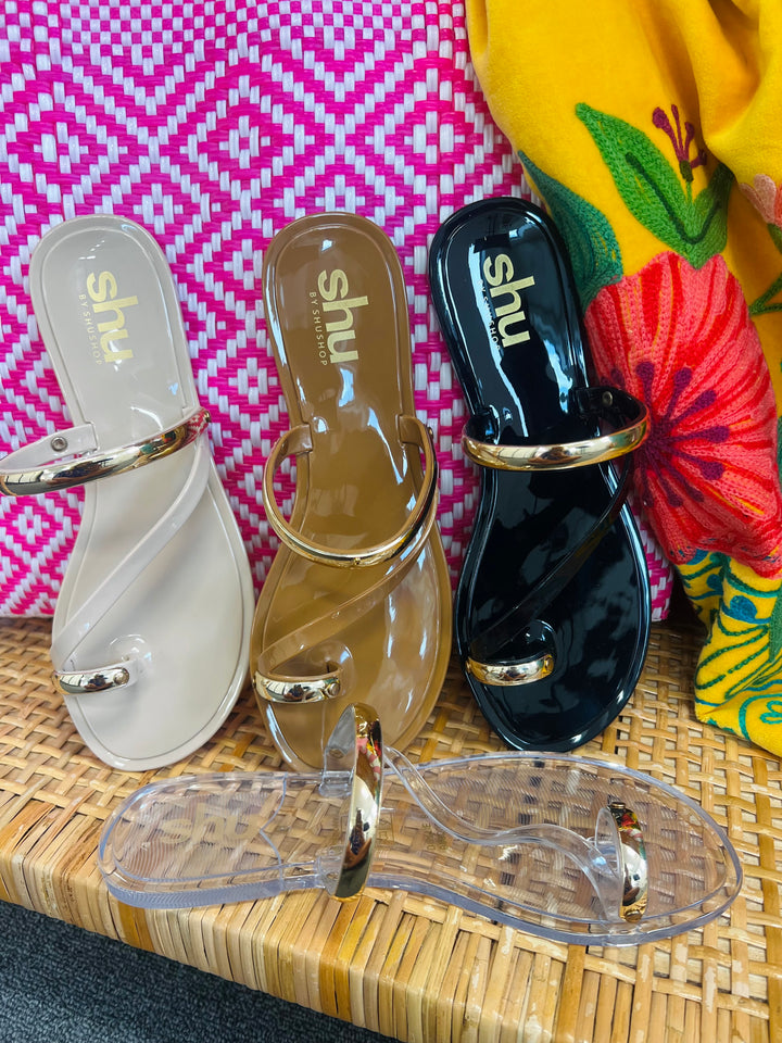 Three pairs of sandals with 'shu' branding on a woven surface.