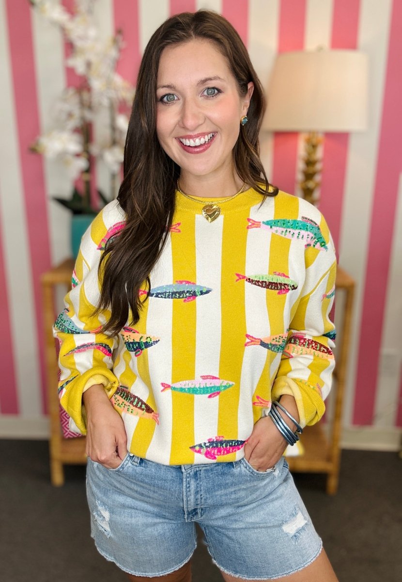 Woman wearing a yellow and white patterned sweater with a striped background