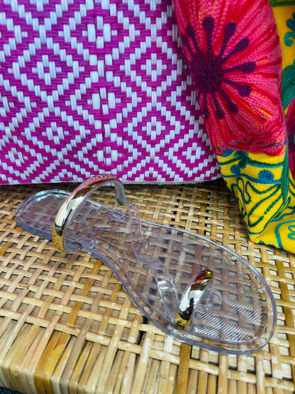 Clear sandal on a woven surface with colorful fabric in the background